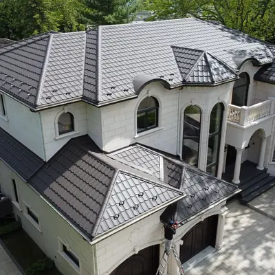Metal tiles dark brown on a large white stone home, Greater Montreal