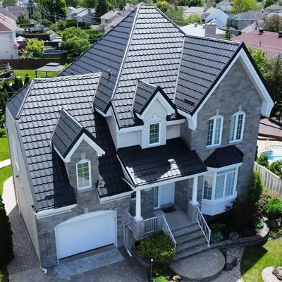 Metal tiles black on a grey stone home, aerial view